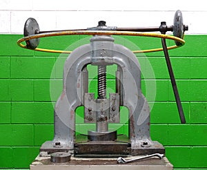 Vintage manual forming press against a green wall