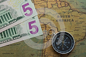 Vintage map of South America with five dolor bills and a compass, close-up