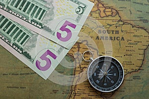 Vintage map of South America with five dolor bills and a compass, close-up photo