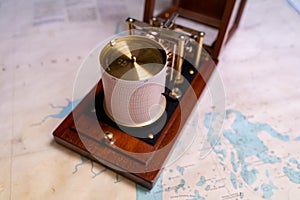 Vintage marine barograph with opened cover standing on a navigational chart