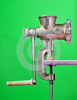 Vintage meat grinder on green pastel background, creative and conceptual photo, minimalist trend.