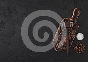 Vintage meat hammer on vintage chopping board and black stone table background. Butcher utensils. Space for text