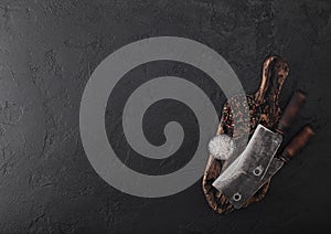 Vintage meat knife hatchet on vintage chopping board and black stone table background. Butcher utensils. Space for text