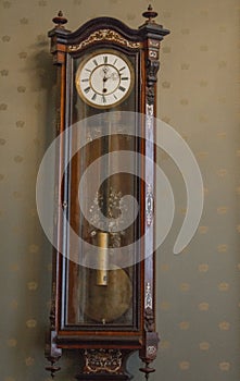 Vintage mechanical wall clock with a pendulum hang on the wall. rare wooden clock in the interior