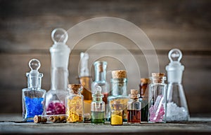 Vintage medications in small bottles on wood desk. Old medical, chemistry and pharmacy history concept background.