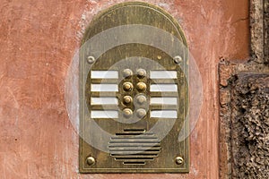 Vintage metal intercom on an old brown painted wall