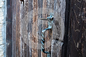 Vintage metal iron door handle on an old door made of natural wood. Horizontal orientation, selective focus. Doorknocker