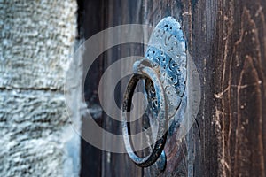 Vintage metal iron door handle on an old door made of natural wood. Horizontal orientation, selective focus. Doorknocker