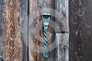 Vintage metal iron door handle on an old door made of natural wood. Horizontal orientation, selective focus. Doorknocker