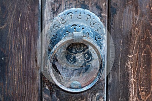 Vintage metal iron door handle on an old door made of natural wood. Horizontal orientation, selective focus. Doorknocker