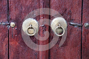 Vintage metal knobs with a ring on an old wooden door close-up