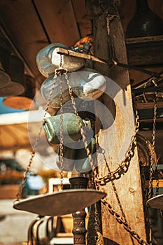 Vintage metal and plastic canteens, copper plates, pots and old rusty balance scales in a shop at antique bazaar