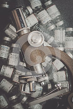 Vintage microscope stands with a collection of small medicine viles in a small science lab