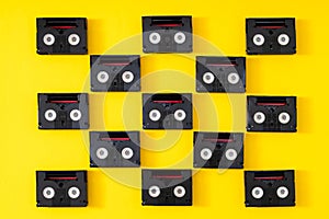 Vintage mini DV cassette tapes used for filming back in a day. Pattern made of plastic video tapes on yellow background