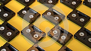 Vintage mini DV cassette tapes used for filming back in a day. Pattern made of plastic video tapes on yellow background