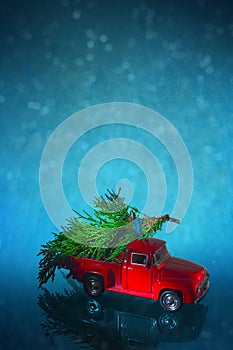 Vintage miniature truck delivers Christmas tree on snow background