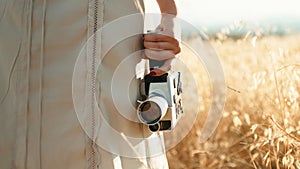 Vintage 8mm cinema camera in the hand of a girl walking in the countryside