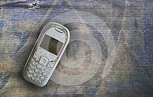 Vintage mobile phone put on old denim background