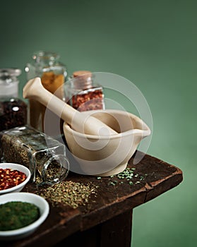 Vintage mortar and pestle with spices and herbs on wooden table