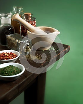 Mortar and pestle with herbs and spices on wood table