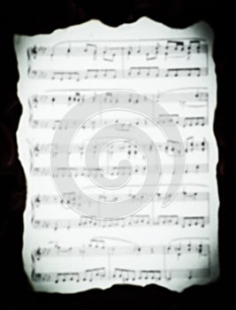 Vintage music sheet with burned edges in the blur.