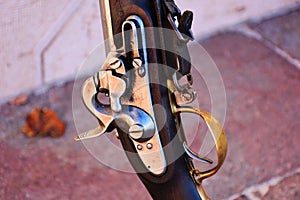 vintage muzzleloading flintlock rifle closeup. shiny metal flint, frizzen cock triggerand