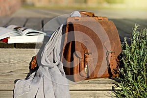 vintage natural leather backpack and books on gray rustic wooden stairs