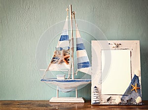 Vintage nautical frame with wooden boat on wooden table. retro filtered image