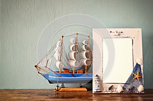 Vintage nautical frame with wooden boat on wooden table. retro filtered image.