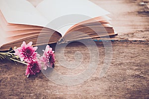 Vintage novel books with bouquet of flowers on old wood background