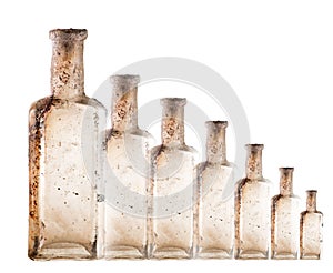 Vintage oil and tincture glass bottles weathered on white background. Duplicated Old bottles with calcium deposits