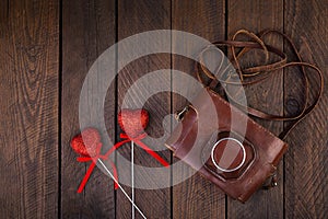 Vintage old camera with hearts on rustic wooden background. Top view