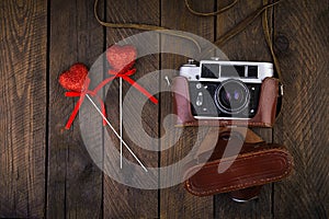 Vintage old camera with hearts on rustic wooden background. Top view