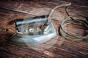 Vintage old-fashioned electric iron on wooden background