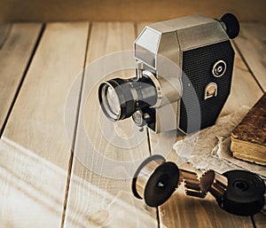 Vintage old movie camera on a wooden table, old book, clothl. Retro photo. Copy space.