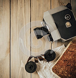 Vintage old movie camera on a wooden table, old book, clothl. Retro photo. Copy space. Top view.