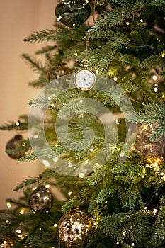 Vintage old retro clocks, gold balls hang on branch of green Christmas tree background. Classical spruce, fir tree, pine New year