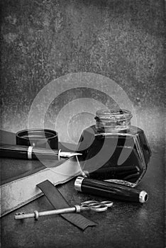 Vintage old romantic still life image of writing paraphrenalia including fountain pen ink bottle and journal book