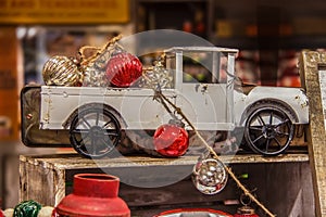 Vintage old rusty metal pick up truck model in rustic setting with Christmas ornaments against blurred background