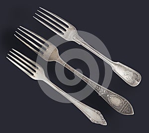 Vintage old worn-out forks isolated on a black background. Retro silverware