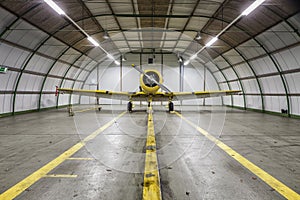 Vintage old yellow war plane inside of a empty hangar