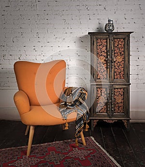 Vintage orange armchair, ornamented cupboard, black scarf and red carpet