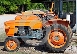 Vintage orange tractors from  Sixties lined up in a gravel road