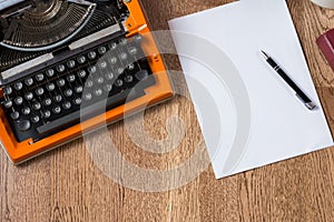 Vintage orange typewriter with paper and pen. Workspace of autor. photo