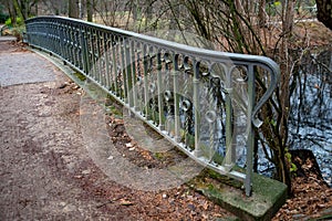 Vintage ornate metal railing fence of old bridge near pond in Tiergarten park of Berlin Germany. Tranquil landscape with nobody.
