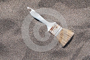 Vintage painting brush on sand. Artist`s brush on beach sand top view with copy space. Decaying painter`s brush close-up.