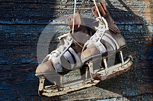 Vintage pair of mens ice skates hanging on a wooden wall with c