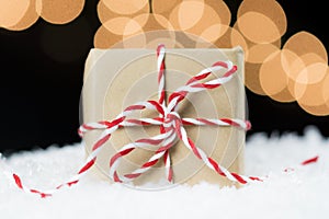 Vintage paper wrapped gift with red and white twine on snow