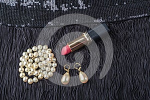 Vintage pearl jewelry and red lipstick on little black dress. Gatsby or Chicago fashion look. Luxury white necklace and earrings.