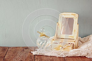 Vintage pearls , antique wooden jewelry box with mirror and perfume bottle on wooden table. filtered image